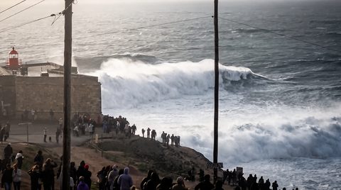 A surfer dropping into a massive breaking wave at Praia do Norte, Nazaré