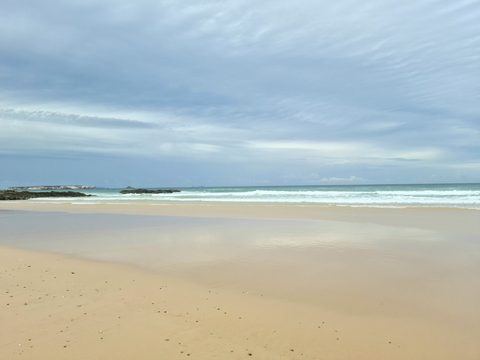 Low tide at Praia da Almagreira, with wet sand reflecting a cloudy sky