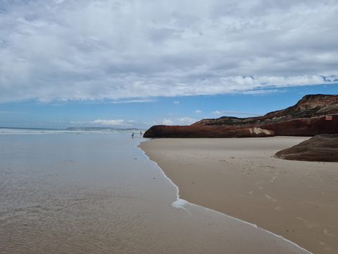 Red sandstone cliffs along the shoreline at Praia da Almagreira