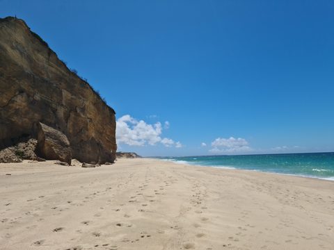 A sandstone cliff beside the wide, empty ocean-side beach at Bom Sucesso