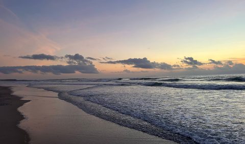 Low rolling waves breaking along the sandy shoreline at Praia d'El Rei
