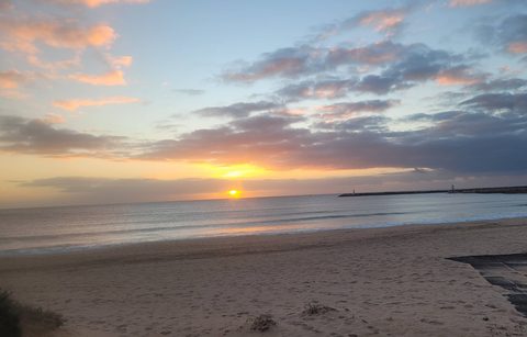 Sunset over the breakwater and beach at Praia do Molhe Leste, Peniche
