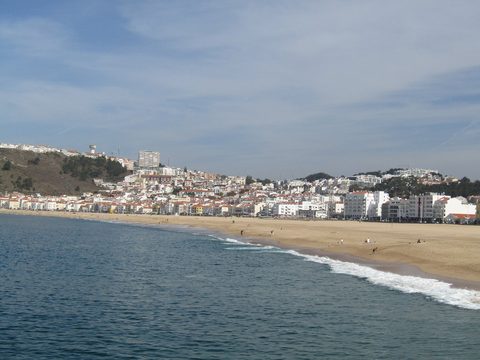 Nazaré town and beachfront seen from the water, with the hillside town behind