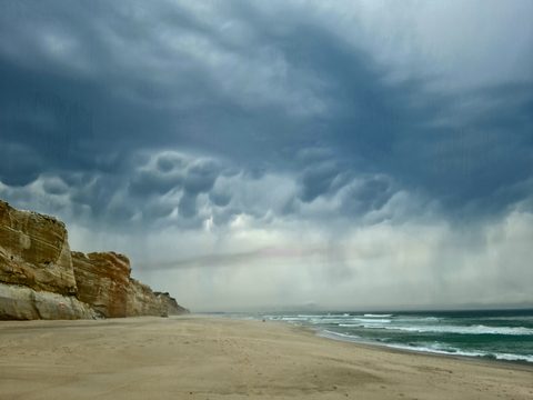 Dramatic storm clouds over the cliffs and sand at Rei Cortiço